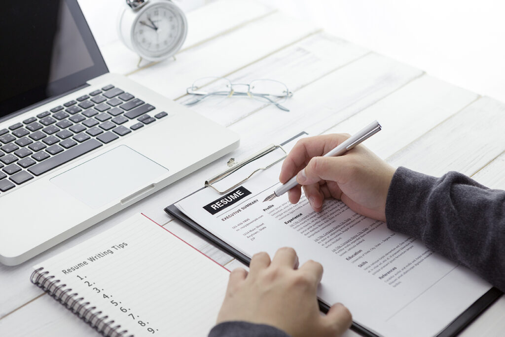 Businessman or HR Manager is reviewing Resume information and paper note with resume writing tips.