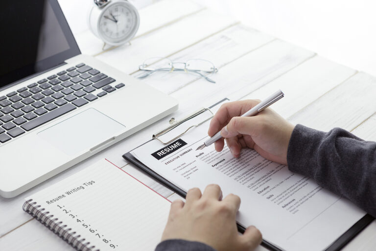 Businessman or HR Manager is reviewing Resume information and paper note with resume writing tips.