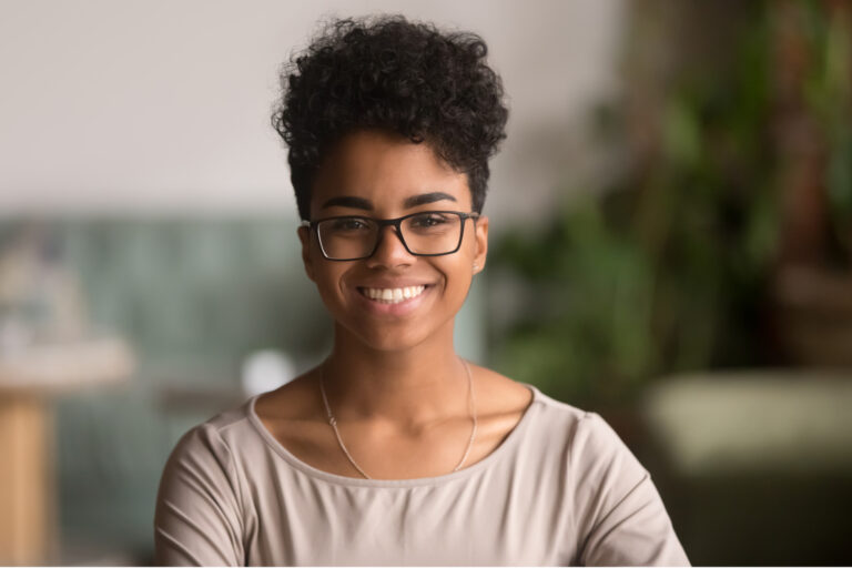 Female African American teen looking into the camera, sits at cafe with blurred background.
